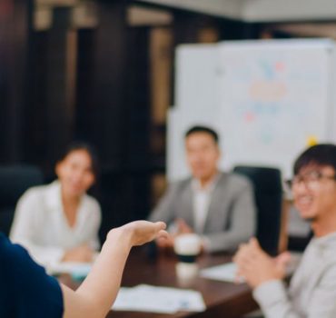Asia businessmen and businesswomen meeting brainstorming ideas conducting business presentation project colleagues working together plan success strategy enjoy teamwork in small modern night office.